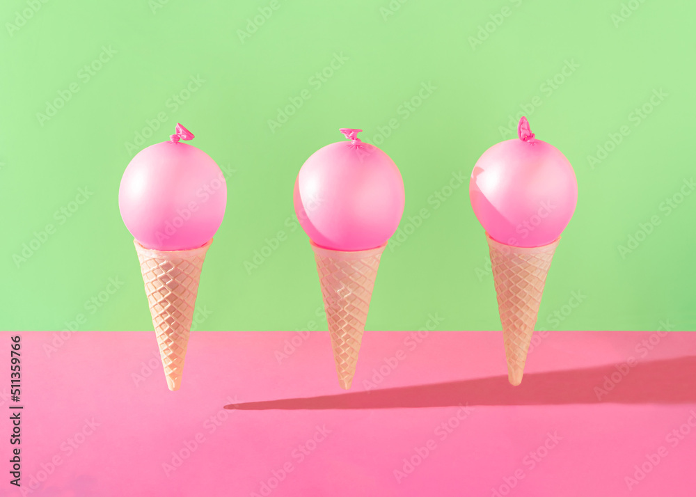 Three ice cream cones with bright pink balloons against vibrant pink and green background. Minimal summer party concept. Creative dessert food idea. Three ice cream cones with bright pink balloons against vibrant pink and green background. Minimal summer party concept. Creative dessert food idea.