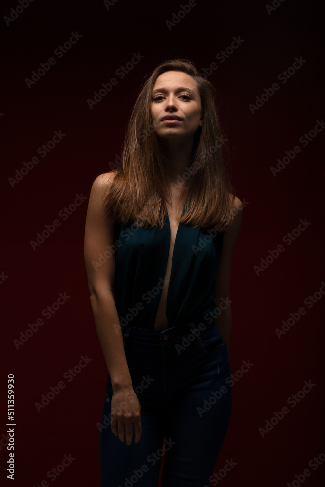 Beautiful lady girl against dark red background. Brunette girl wearing fancy shirt looking at camera..