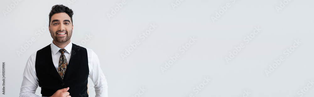 happy muslim man in vest looking at camera isolated on grey, banner. happy muslim man in vest looking at camera isolated on grey, banner.