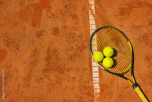  A yellow tennis ball and tennis racket lies on the clay court. © Igor Link