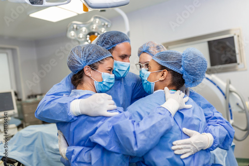 Partial view of hard-working male and female hospital team in full protective wear standing together in group embrace