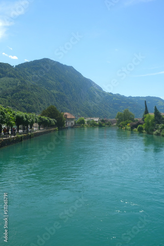 Fototapeta Naklejka Na Ścianę i Meble -  Selective focus picture of green Aare River in Interlaken with mountain and some house insight.