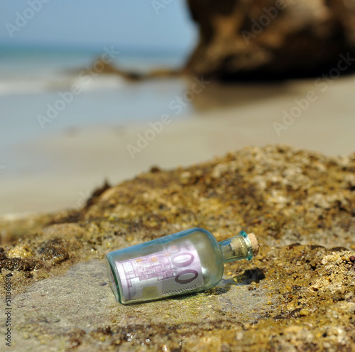 Bottiglia ritrovata sugli scogli del mare con dentro una banconota da cinquecento euro. 500 euro. Riciclaggio di denaro. Immagine per illustrare il trading di valuta.