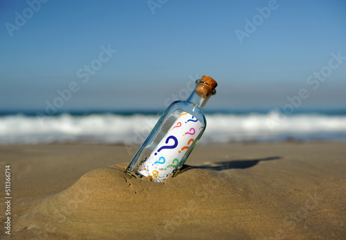 Botella encontrada en la playa con preguntas de colores en su interior. Muchas incógnitas. Concepto de incertidumbre sobre el futuro