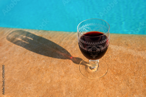 kryształowy kieliszek z czerwonym winem na skraju basenu photo