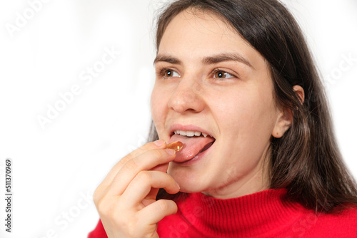 A woman takes an omega 3 capsule on a white background  copy space for text