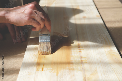 Covering and impregnate  a wooden board with varnish by hand with a paintbrush close-up