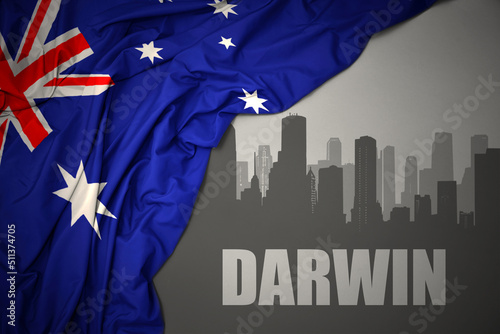 abstract silhouette of the city with text Darwin near waving national flag of australia on a gray background.