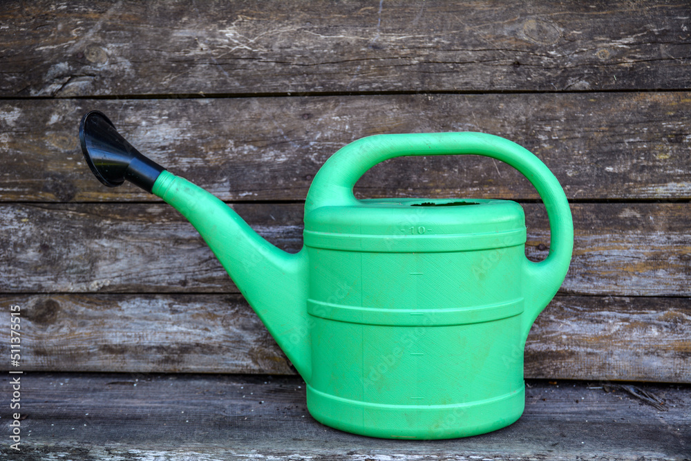Green plastic sprinkling can outdoor in garden. Watering can. Green plastic sprinkling can outdoor in garden. Watering can.