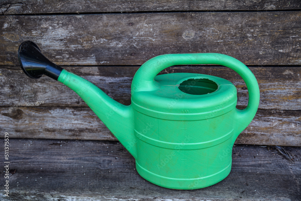 Green plastic sprinkling can outdoor in garden. Watering can. Green plastic sprinkling can outdoor in garden. Watering can.