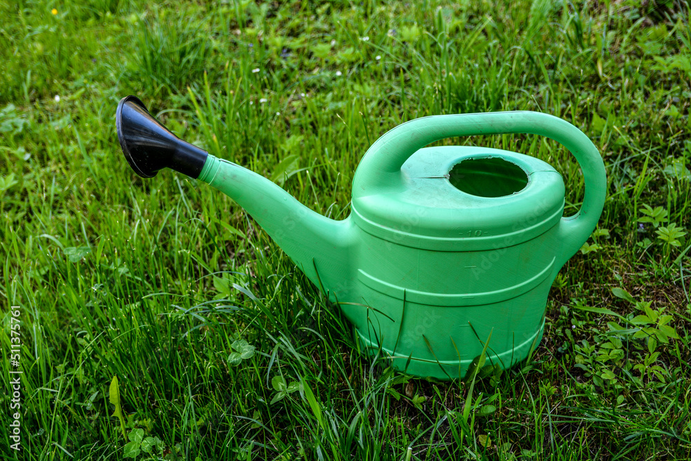 Green plastic sprinkling can outdoor in garden. Watering can. Green plastic sprinkling can outdoor in garden. Watering can.