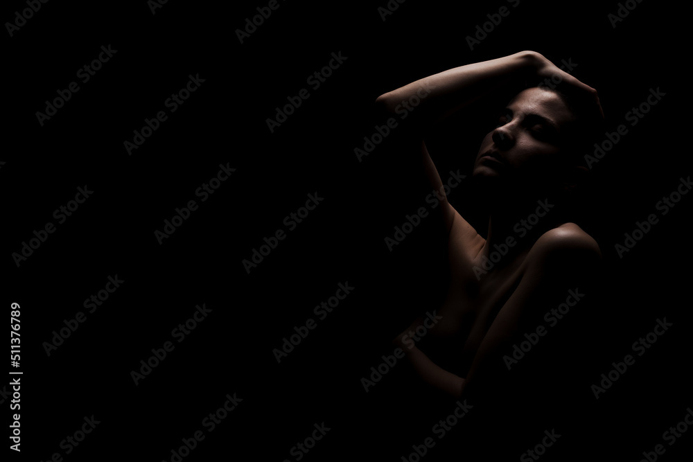 Portrait of a girl with short hair against dark background. Side lit contour slhouette...