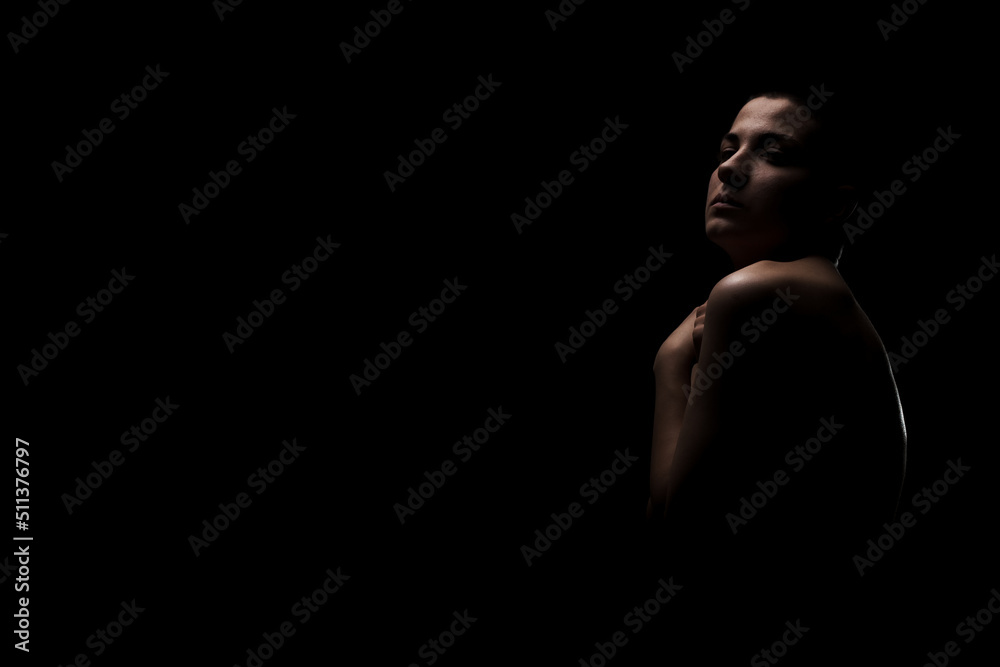 Portrait of a girl with short hair against dark background. Side lit contour slhouette...