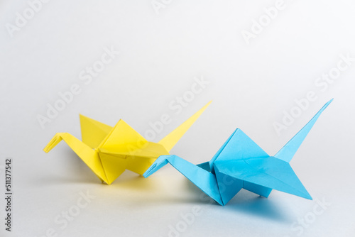 Traditional Japanese origami cranes made of blue and yellow paper on a white background. Pair of colorful paper birds. origami birds.