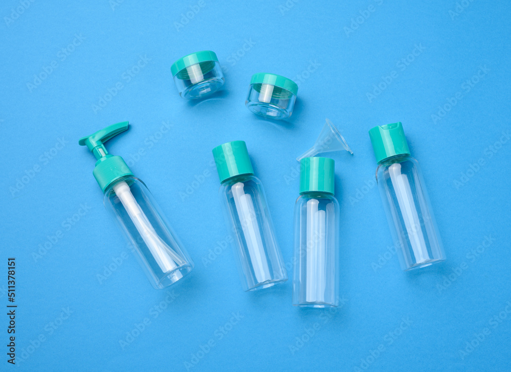Various transparent empty plastic bottles and jars for cosmetics on a blue background, top view Various transparent empty plastic bottles and jars for cosmetics on a blue background, top view