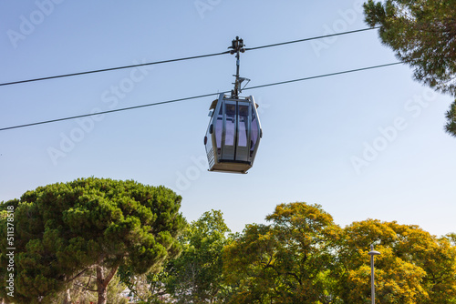 cable car cabin moving over trees on blue sky