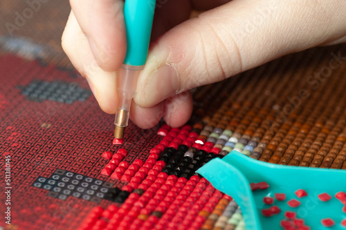 Collecting diamond embroidery, diamond mosaic. Colored crystals. Needlework. Creation. CloseUp.