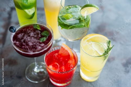 Six summer refreshing cocktails with lemon and mint, vegan beverages on dark marble textured table, heathy lifestyle, flat lay