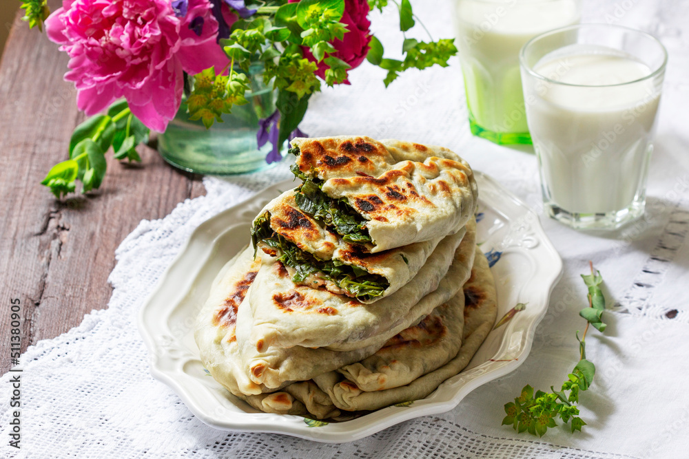 Traditional Armenian flatbread with greens zhengyalov hats, served with yogurt on the background of a bouquet.