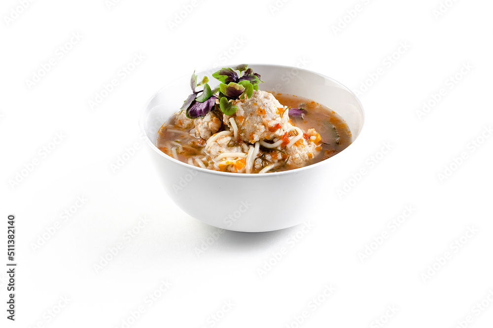 Isolated soup with chicken meatballs and a sprig of basil on a white background Isolated soup with chicken meatballs and a sprig of basil on a white background