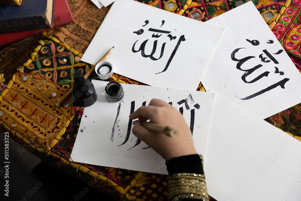 Foto de close up muslim girl hands writing Arabic text with bamboo pens