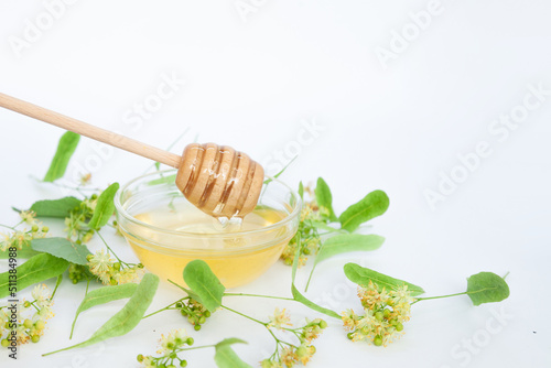 Natural linden honey with linden flowers on a white background