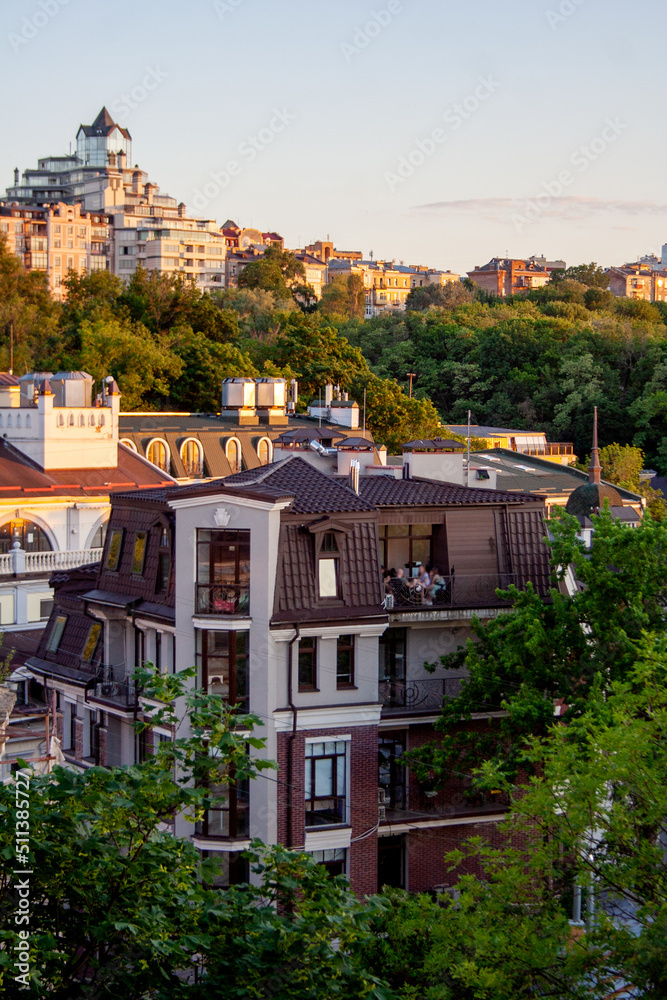 Urban hill with trees and buildings rooftops under sunset sky Urban hill with trees and buildings rooftops under sunset sky