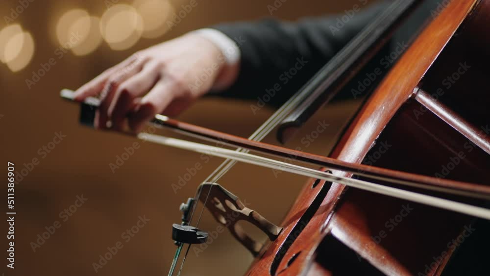 closeup view of violoncello and hands of musician, cellist is playing cello in symphonic orchestra