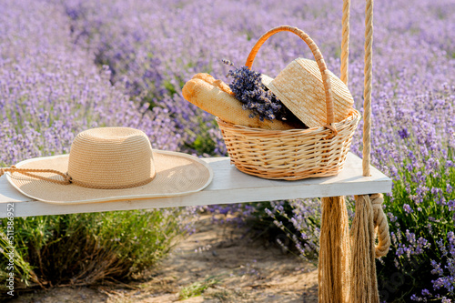 lavender field, straw hat and picnic basket on a swing, a symbol of summer va...
