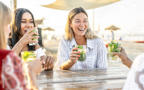 Fotografiet Young attractive women drink mojito on the beach while listening chill music - t