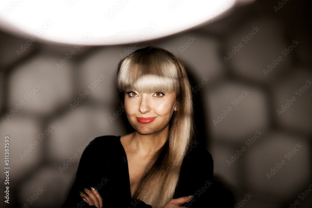 Beautiful girl with blond bangs fringe wearing black fashionable fancy dress posing under shadows. .
