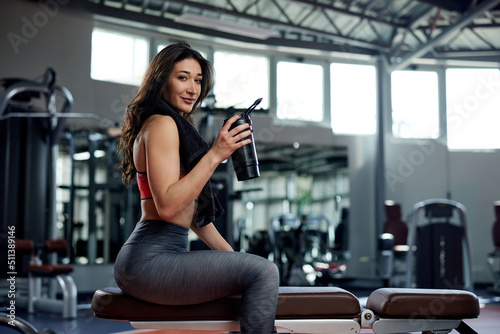 Young active woman taking a break in the gym and drinking protein shake.