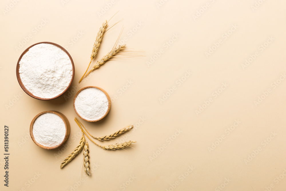 Flat lay of Wheat flour in wooden bowl with wheat spikelets on colored background. world wheat crisis Flat lay of Wheat flour in wooden bowl with wheat spikelets on colored background. world wheat crisis
