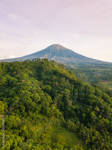 Drone photo of Mount Sumbing with hill overgrown by dense of trees in the morning. Central Java, Indonesia