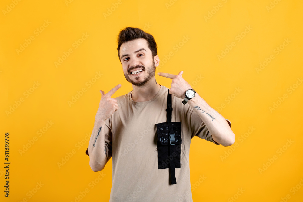 Cheerful young man wearing t-shirt posing isolated over yellow background cheerful showing and pointing with fingers teeth and mouth. Dental health concept. Cheerful young man wearing t-shirt posing isolated over yellow background cheerful showing and pointing with fingers teeth and mouth. Dental health concept.