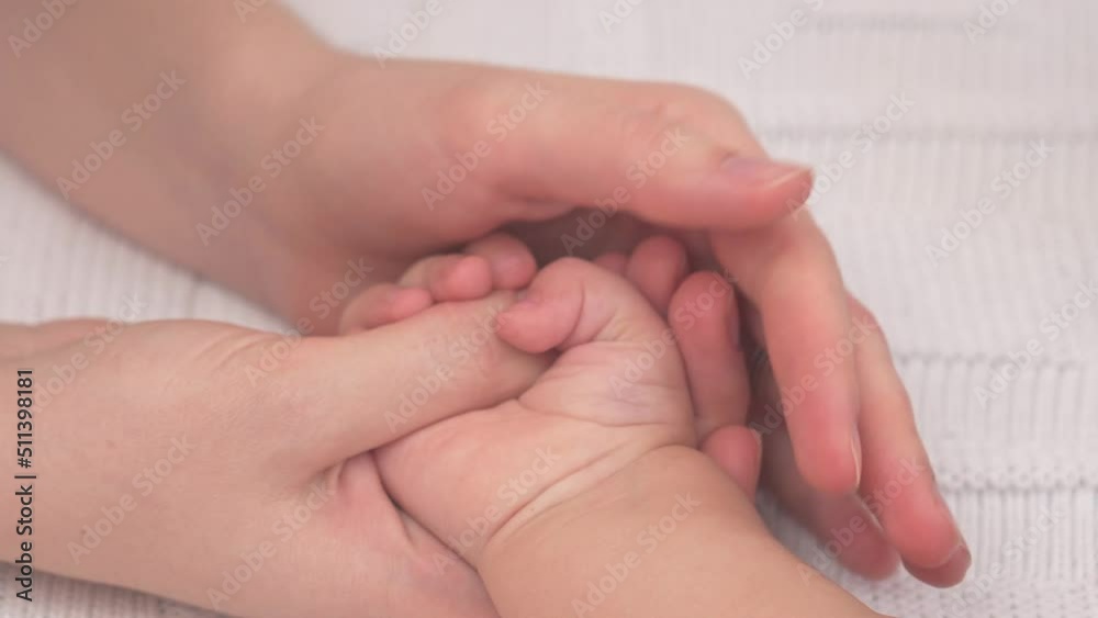 Mom holds the palm of a sleeping baby and gently strokes it, selective focus Mom holds the palm of a sleeping baby and gently strokes it, selective focus