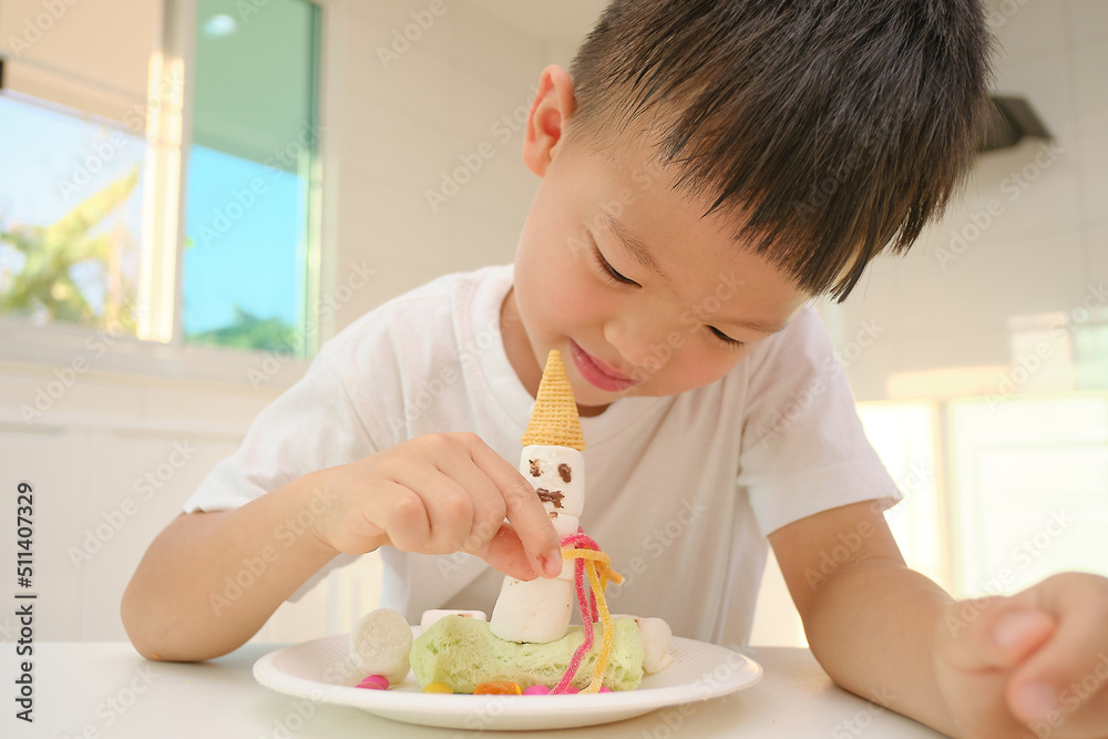 Cute little Asian kindergarten boy child sitting at the kitchen making easy and fun Marshmallow Snowman edible craft for kids, Montessori education, Homeschooling, Soft and selective focus Cute little Asian kindergarten boy child sitting at the kitchen making easy and fun Marshmallow Snowman edible craft for kids, Montessori education, Homeschooling, Soft and selective focus