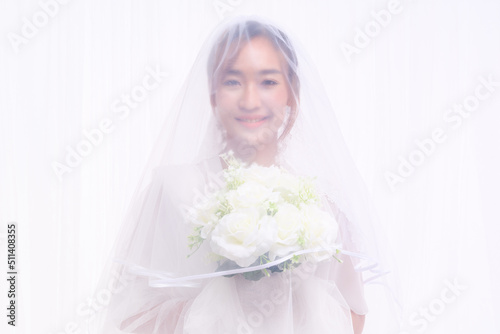 bride in white gown with veil holding flower bouquet