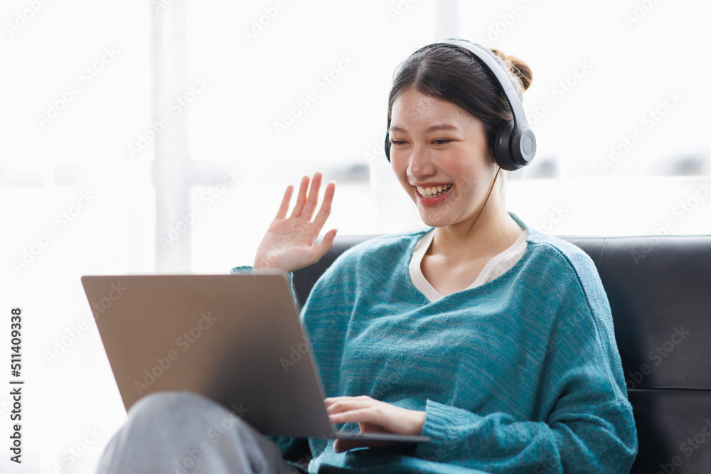 Asian young female student sitting at the table, using laptop and headphones when studying. Asian young female student sitting at the table, using laptop and headphones when studying.
