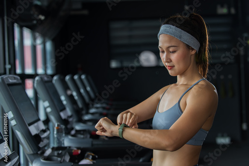 woman working out in a gym. woman lookinng time and heart on Smart watch.