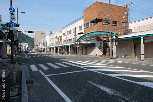 人通りの少ない時間帯の交差点と信号機、道路の両側に商店がある大通り（日本の地方都市）