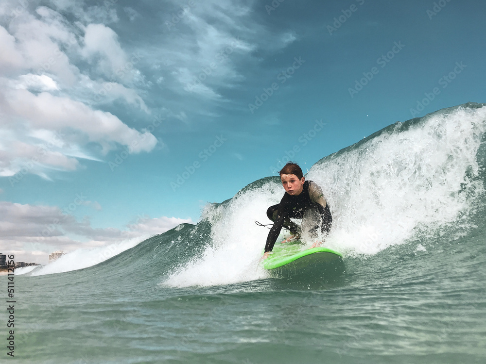 Boy catching wave on foam surfboard taken in water Boy catching wave on foam surfboard taken in water