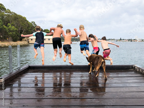 Group of kids jumping off a wharf into the water photo