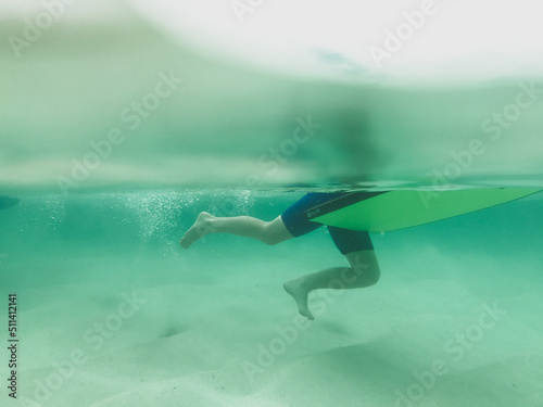 Boys legs underwater pushing off ground holding onto body board photo