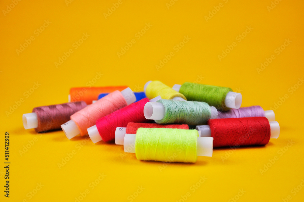 Reels with multicolored threads on a yellow background. Blur. Reels with multicolored threads on a yellow background. Blur.