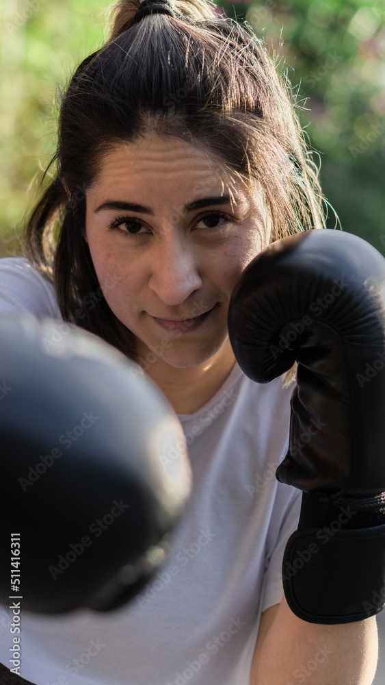 Pretty woman looking at camera posing with boxing gloves on fists.
