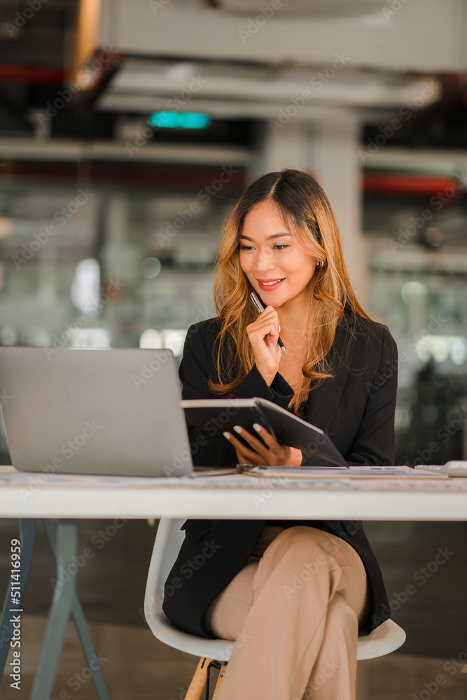 Asian female freelancer working using laptop computer in modern office make an account analysis report real estate investment information Business finance and tax system concept, vertical image. Asian female freelancer working using laptop computer in modern office make an account analysis report real estate investment information Business finance and tax system concept, vertical image.