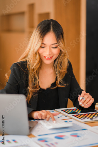 Smiling Asian businesswoman working on laptop in office accountant concept finance expert analysis business report graph financial chart corporate economy Banking Market Research vertical picture