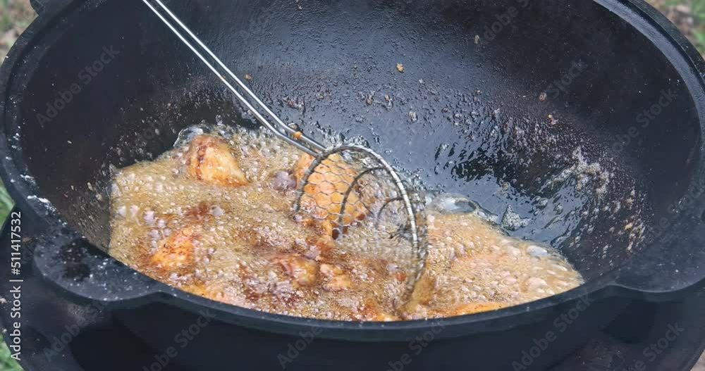 Cooking food deep fried crispy chicken wings in cauldron a boiling hot oil Cooking food deep fried crispy chicken wings in cauldron a boiling hot oil