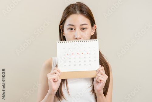 Menstruation, periods cycle day of monthly, hurt asian young woman, female hand holding, marking symbol on calendar for missed and delay or late. Medical, healthcare, gynecological concept. Copy space
